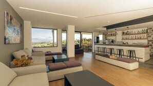 Uma sala de estar moderna com sofá, pufes e mesa de centro. Há uma área de cozinha com balcão e banquetas.