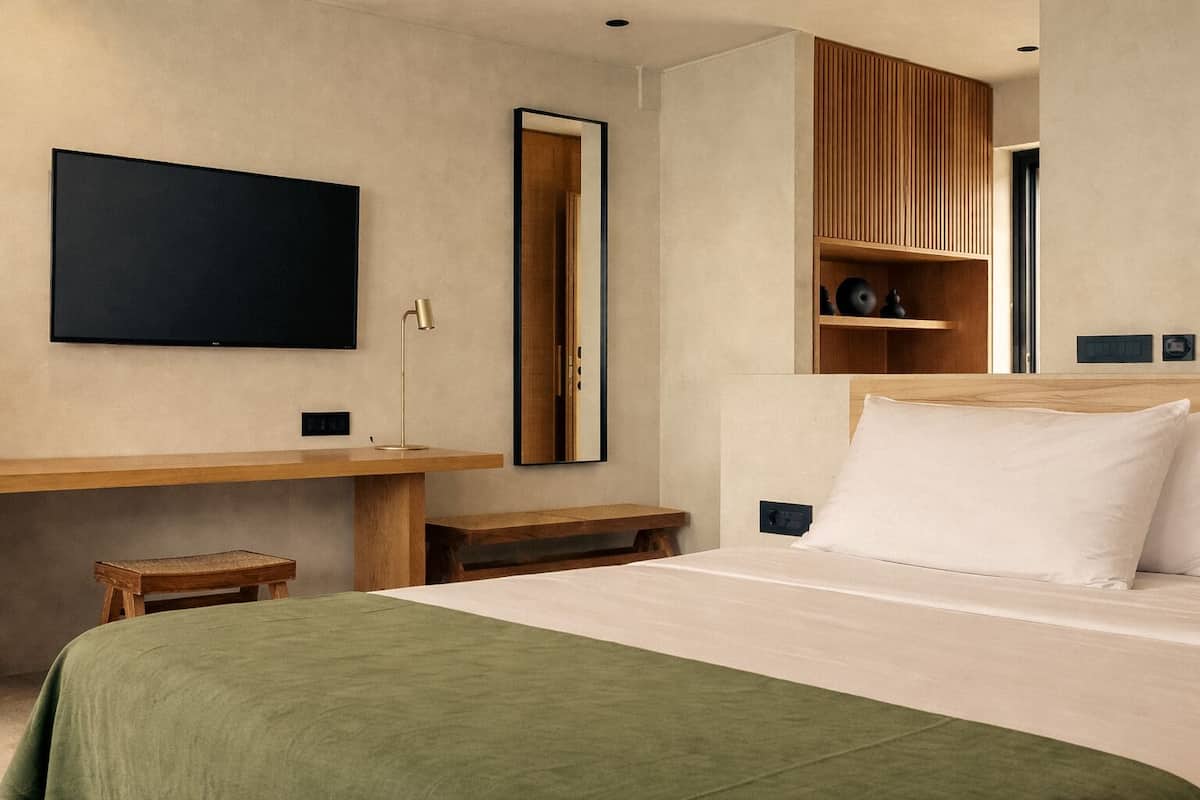 Una habitación de hotel moderna con cama, escritorio, televisor y espejo.