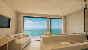 Quarto de hotel moderno com uma varanda grande, um sofá, uma escrivaninha e um banheiro com espelho amplo.