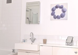 A modern bathroom with a white vanity, a glass shower enclosure, and a wall-mounted mirror. - Dress Circle (Eastbourne)