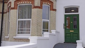 A corner building with a green door, white steps, and large windows.