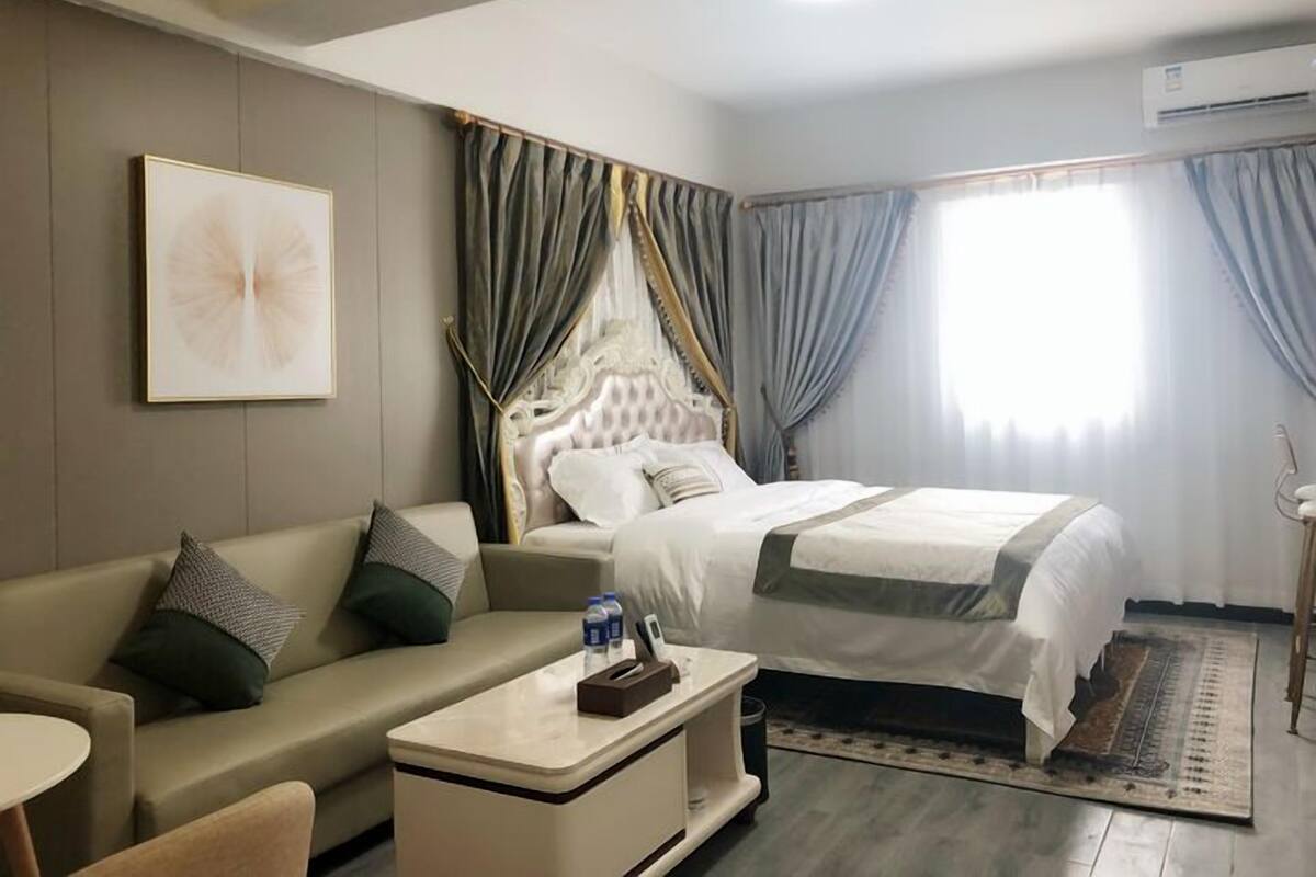 A hotel room with a bed, a sofa, a small table, and a bedside table.