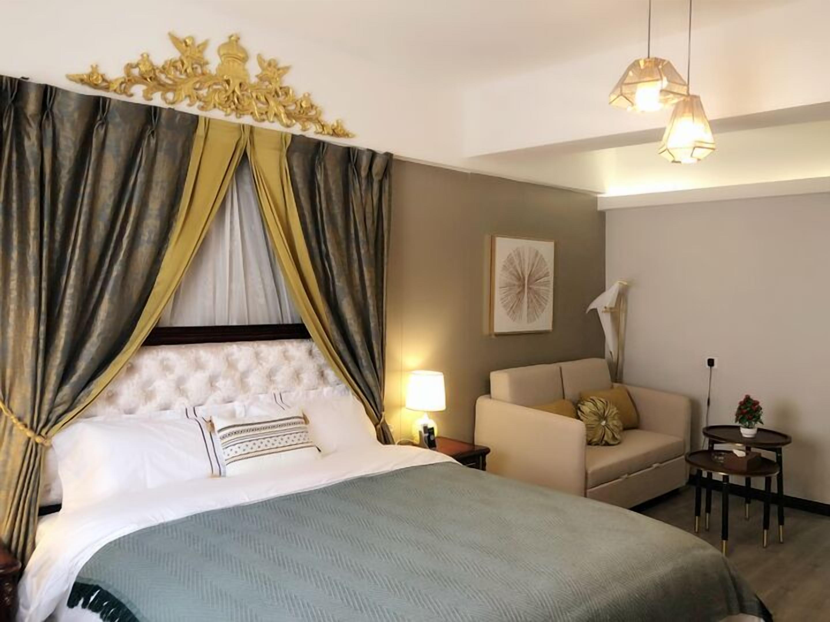 A hotel room with a large bed, a sofa, a small table, and a decorative canopy.