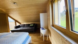A bedroom with a bed, a sofa, a small white table with flowers, and a window with a view of greenery. - Rose house in Schwarzenberg (Schwarzenberg)