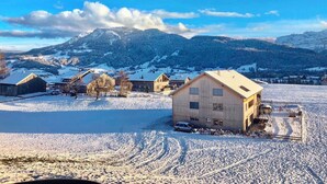 A snow-covered village with traditional wooden houses, a clear sky, and mountains in the background. - Rose house in Schwarzenberg (Schwarzenberg)