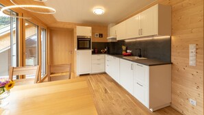 A modern kitchen with wooden cabinetry, a built-in oven, and a black countertop. - Rose house in Schwarzenberg (Schwarzenberg)
