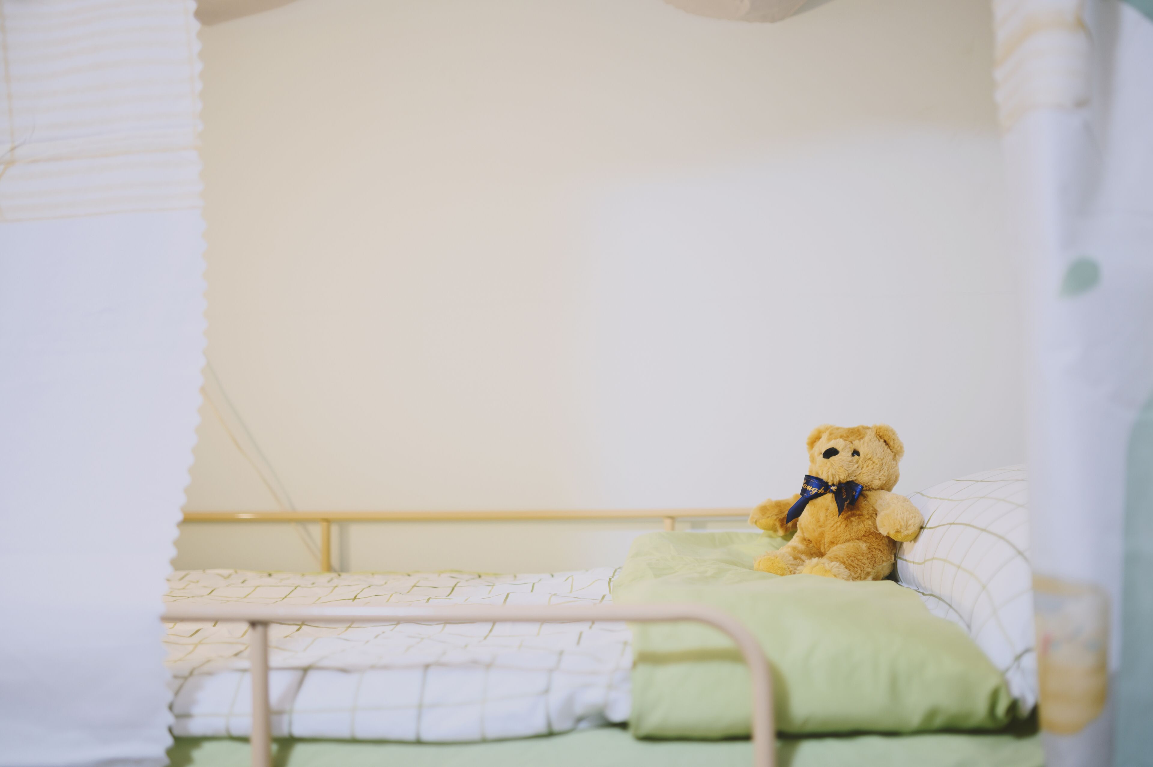Un letto con un cuscino verde e un orsacchiotto sopra.