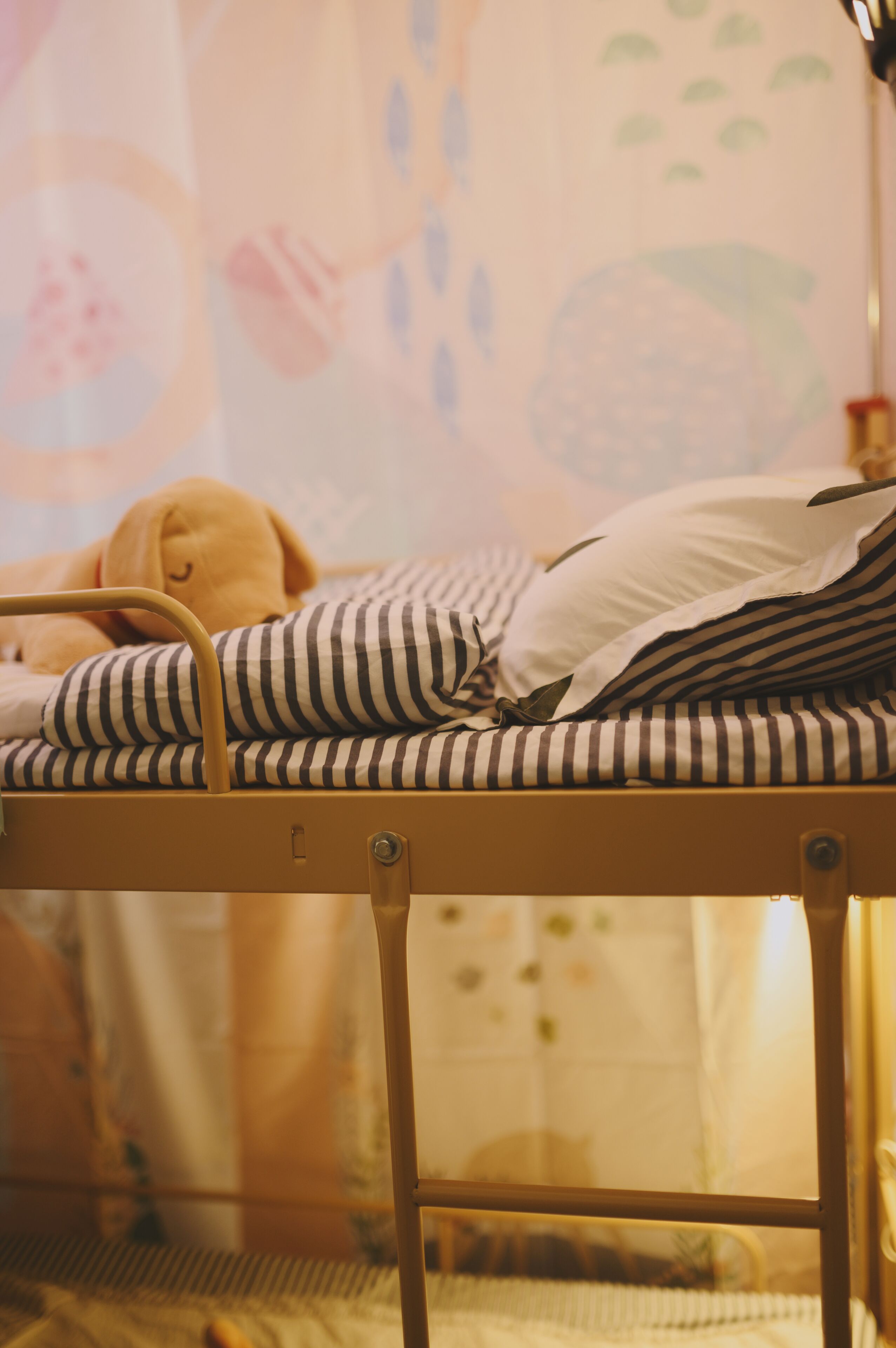 A bunk bed with striped bedding and a teddy bear.