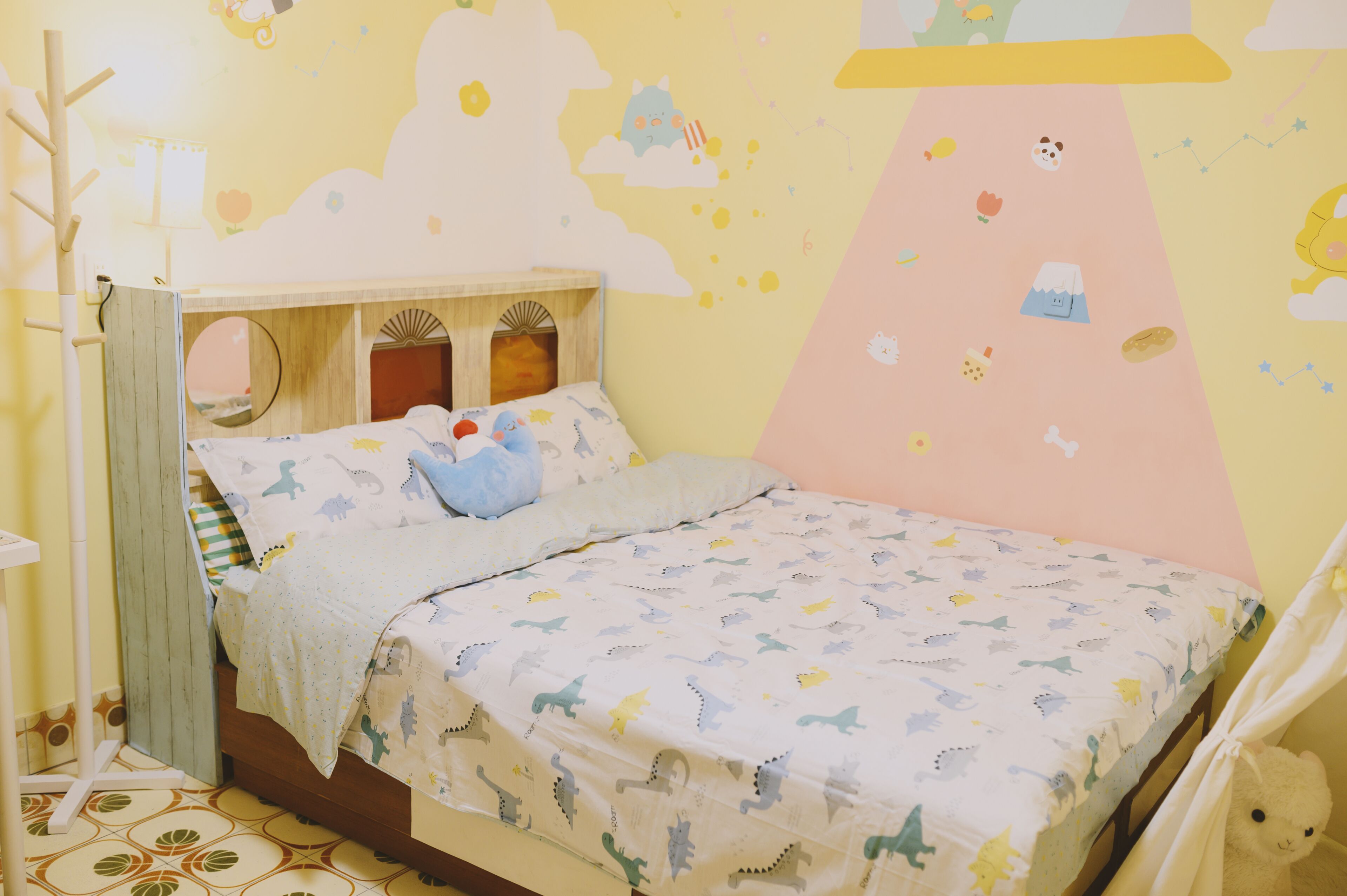 A child's bedroom with a bed, a small table, and a wall mural.