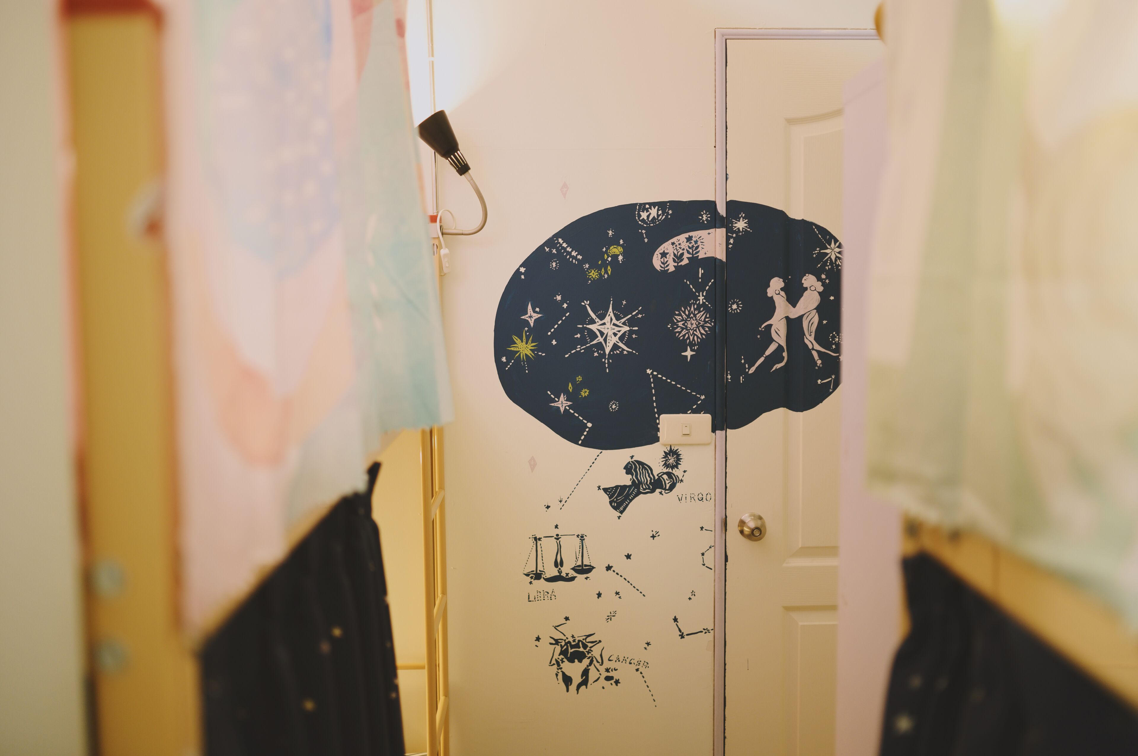 A hallway with a door featuring a wall decal of zodiac signs and constellations.