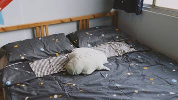 A bed with a space-themed bedspread, a pillow with the word "HUG" on it, and a checkered pillow.