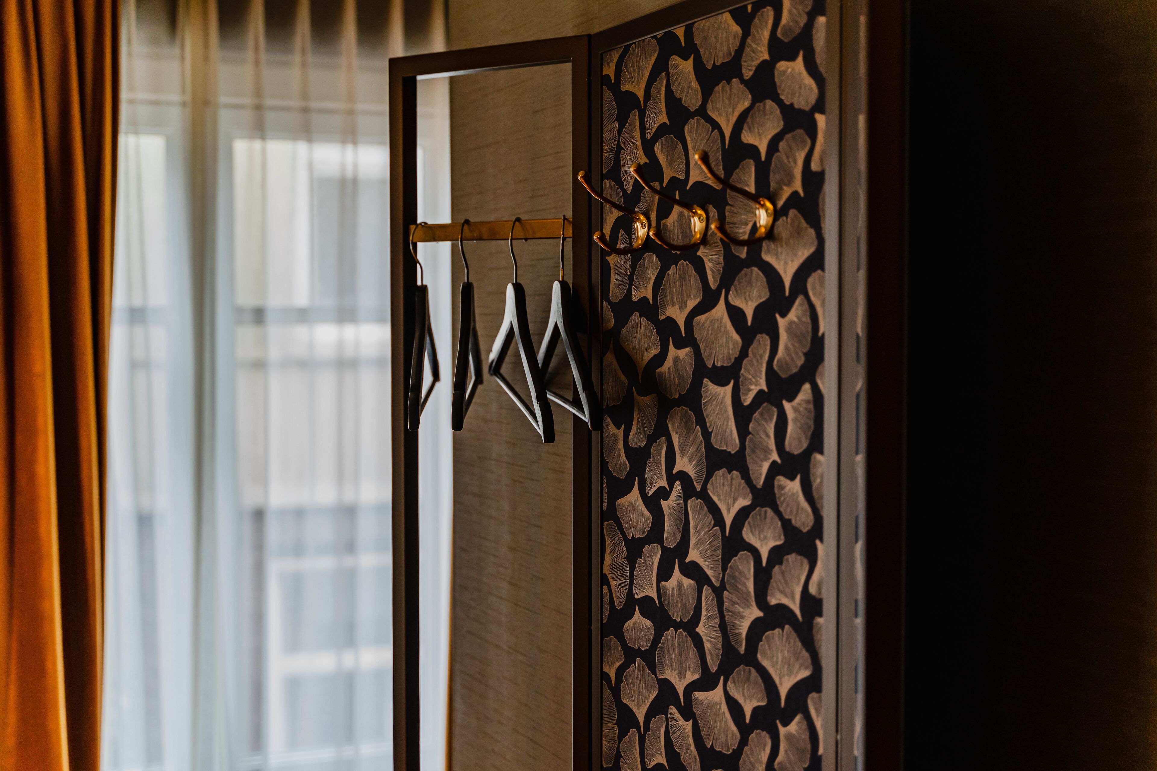 A room with a wooden partition, a coat rack with hangers, and a patterned wall.