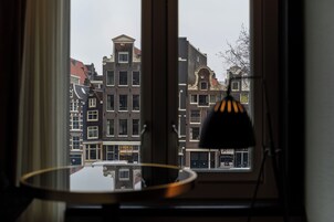 Une vue par la fenêtre, avec une lampe qui reflète une rangée de bâtiments traditionnels.