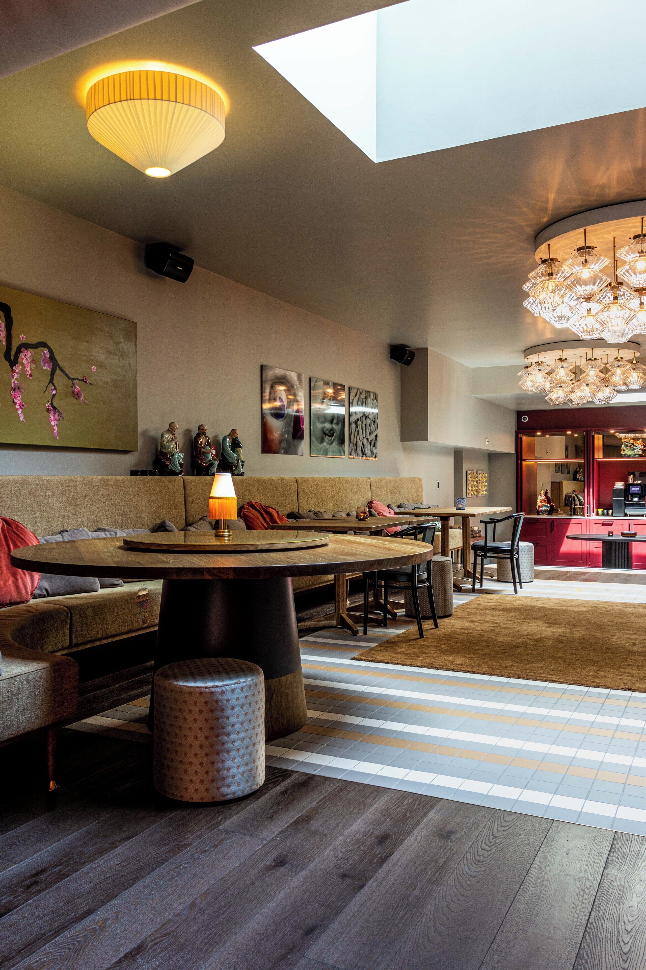 A modern interior with a wooden dining table, a sofa, and a large chandelier.