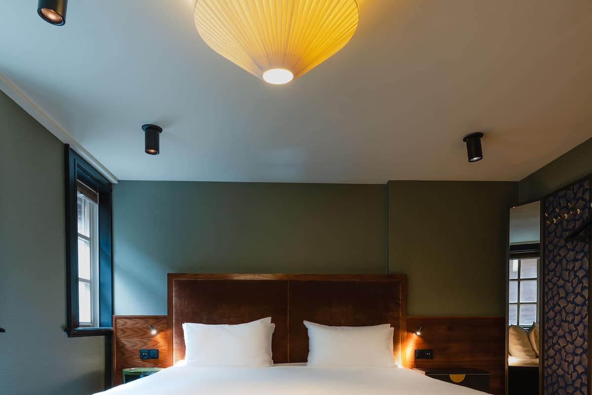 Ein großes Bett mit Holz-Kopfteil, zwei Nachttische und eine Wandlampe.