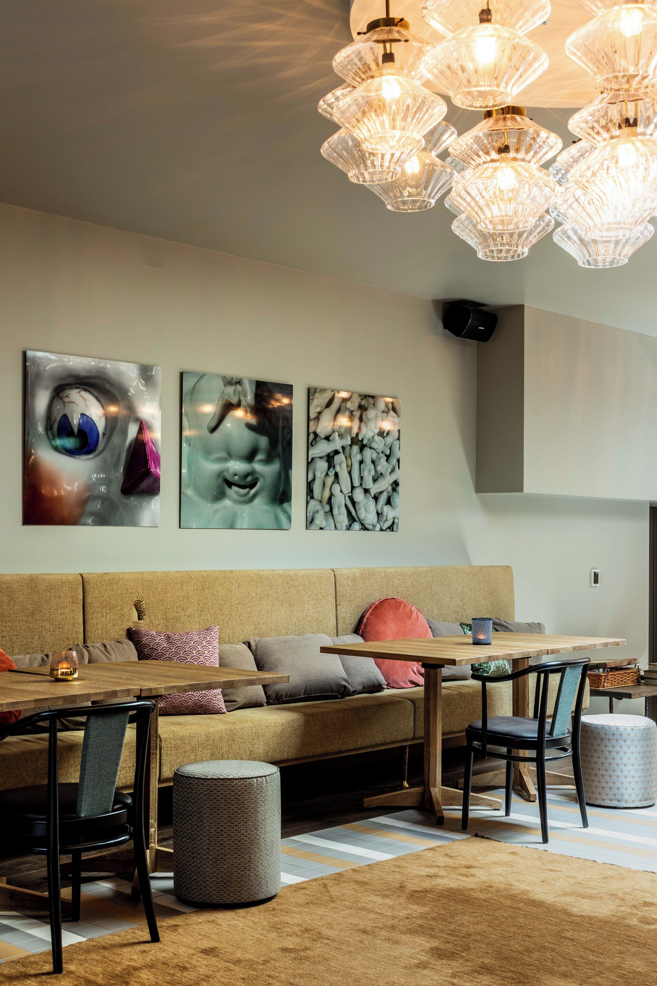 A modern living room with a sofa, dining table, chairs, and a unique chandelier.