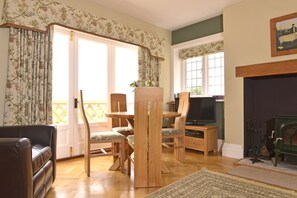 Ein Wohnzimmer mit einem Holzespeisetisch, Stühlen, einem Ledersofa, einem Kamin und einem Fernseher.