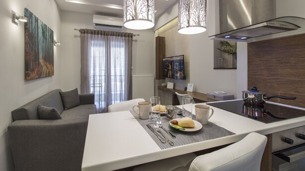 A modern dining area with a central island, a sofa, and a kitchen with a stove. - InCity El Flow, Double Flat (Thessaloniki)