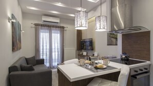 A modern kitchen with a central island, a dining area with a white table, and a grey sofa. - InCity El Flow, Double Flat (Thessaloniki)