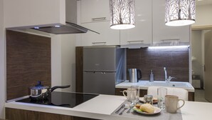 A modern kitchen with a built-in stove, stainless steel appliances, and a dining area with a table set for two. - InCity El Flow, Double Flat (Thessaloniki)