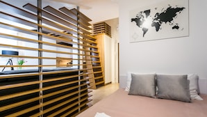 Une chambre d’hôtel moderne avec une cloison en lattes de bois, un lit avec des oreillers gris et une carte du monde accrochée au mur.