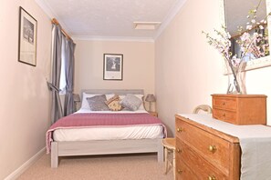 A bedroom with a bed, a dresser, a mirror, and two framed pictures on the wall. - Littledale Haven (Eastbourne)