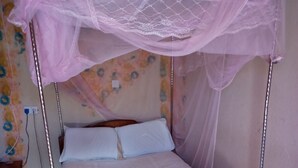 Ein Bett mit Baldachin, weiße Bettwäsche und ein gerolltes Handtuch.