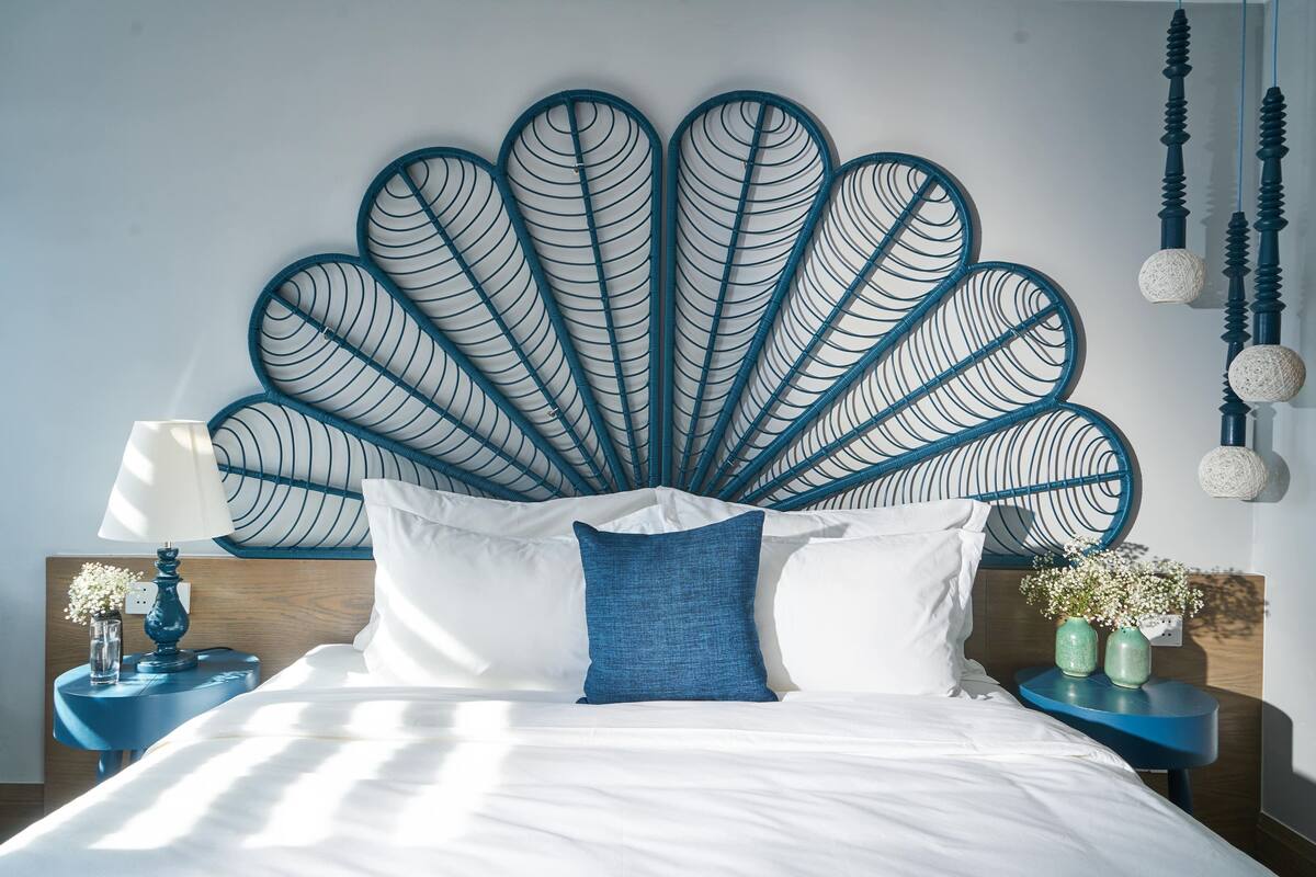 Ein Bett mit weißen Bettwäsche, einem blauen Kopfkissen und einer dekorativen Wandverkleidung.