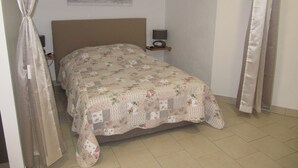 A bedroom with a bed, a nightstand, a lamp, and a painting on the wall. - Cabris, charming Provencal villa, sea view, near the village (Cabris)