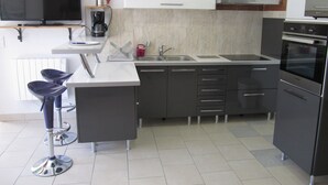 A modern kitchen with a flat-screen TV, a coffee maker, a sink, and a built-in oven. - Cabris, charming Provencal villa, sea view, near the village (Cabris)