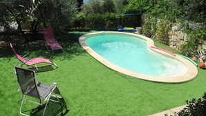 A backyard with a swimming pool, artificial grass, and two lounge chairs. - Cabris, charming Provencal villa, sea view, near the village (Cabris)