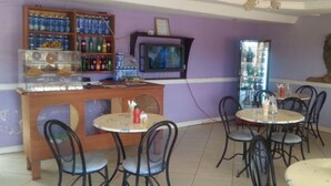 A restaurant with purple walls, a television, and a lion statue. - GMT Guest House (Mai Mahiu)