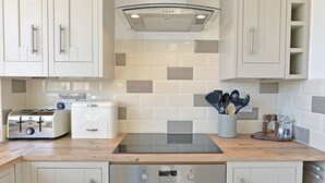 A modern kitchen with white cabinets, a built-in oven, a toaster, and a stove. - Pacific Heights (Eastbourne)