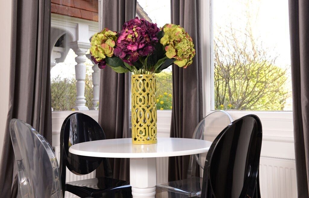 Uma mesa branca redonda com um vaso decorativo de flores.
