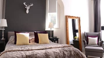 Quarto com cama grande, decoração de cabeça de veado, espelho e uma cadeira.