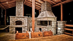 An outdoor stone fireplace with a chimney, wooden benches, and a covered roof structure. - Villa Theano - 4 bedroom villa close to the beach (Agios Nikolaos)