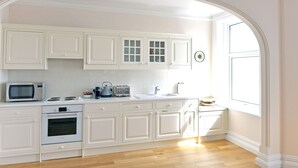 A modern kitchen with white cabinetry, a Bosch oven, a microwave, a kettle, and a toaster. - Sea Dreams (Eastbourne)