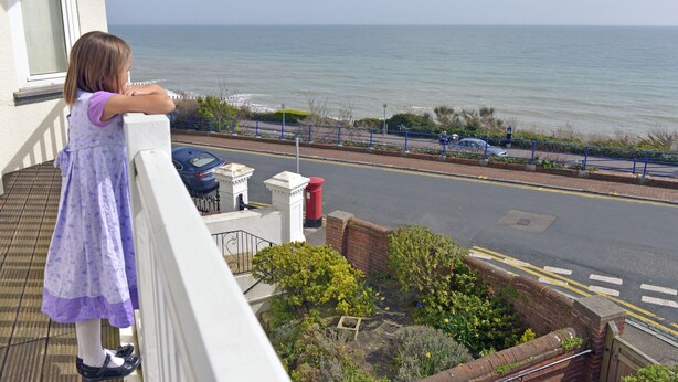 A balcony with a view of the sea, a street with parked cars, and a red post box. - Sea Dreams (Eastbourne)