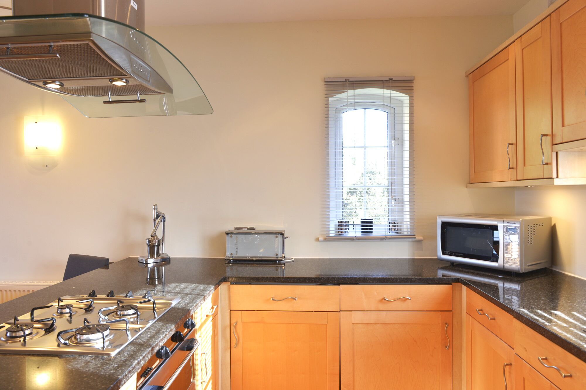 A kitchen with a gas stove, a microwave, and wooden cabinets.