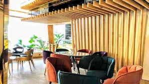 A modern dining area with wooden slats, comfortable chairs, and a view of greenery outside. - Grace Cox Smart Hotel (Cox's Bazar)
