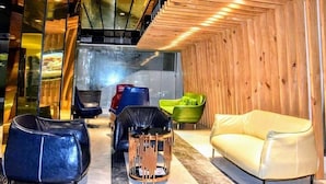 A modern interior with a wooden wall, a yellow sofa, and various chairs. - Grace Cox Smart Hotel (Cox's Bazar)