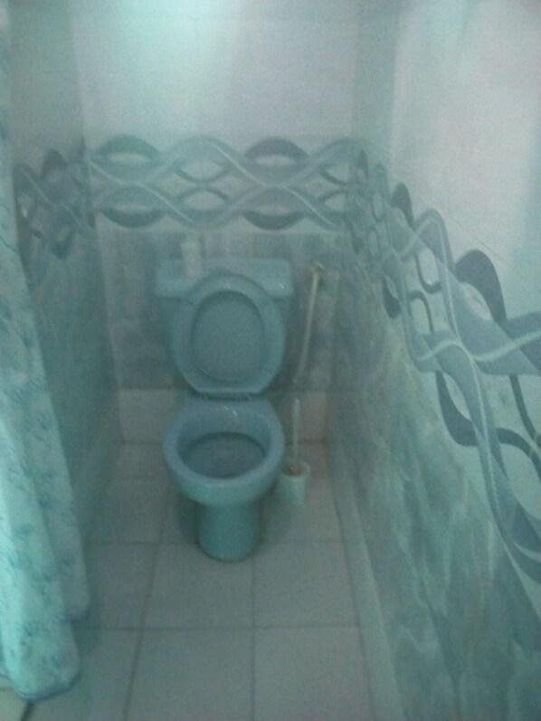 Une salle de bain avec des toilettes et un bidet, un carrelage au sol et un papier peint à motifs.