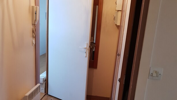 Een gang met houten vloer, een witte deur en een radiator.