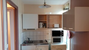 Een kleine keuken met een wasmachine, magnetron en spoelbak.