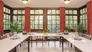 A dining room with a long table, chairs, and curtains. - Hotel Buchenhof (Worpswede)