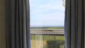 A room with a view of a green landscape through a window, a chair, and a small table. - The Burrows Bed and Breakfast (Pembroke)