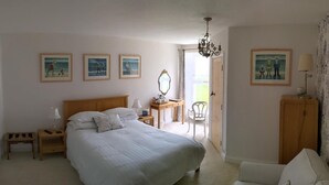 A bedroom with a large bed, a desk, a chair, a wardrobe, and a chandelier. - The Burrows Bed and Breakfast (Pembroke)