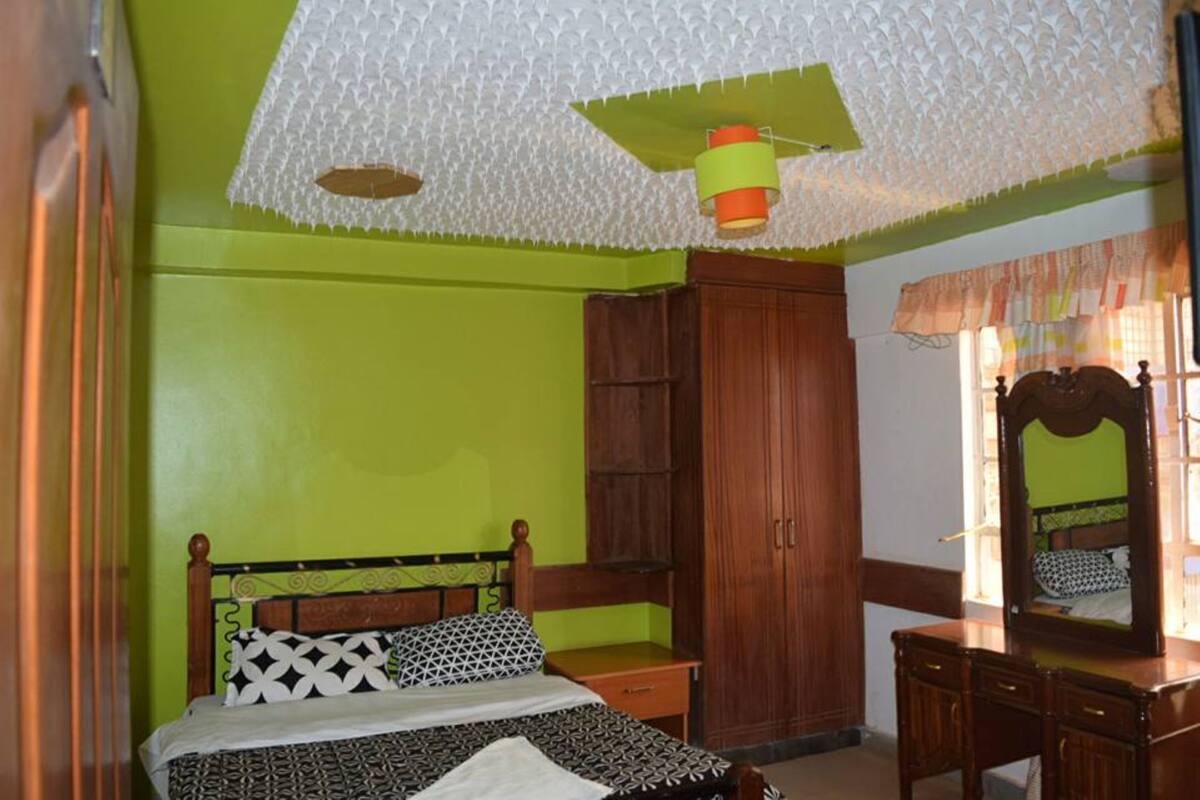 Un dormitorio con cama, armario de madera y cómoda.