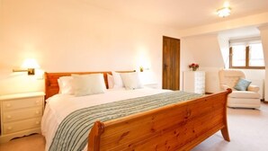 A bedroom with a wooden bed, bedside tables, a chair, and a dresser. - Cottage at Friston Down (Eastbourne)