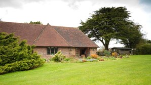 A brick house with a sloped roof and a large tree in the front yard. - Cottage at Friston Down (Eastbourne)